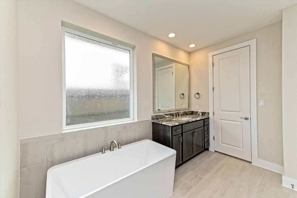 1221 Stormy Drive Georgetown, TX 78628 - Photo 22 of 33 a bathroom with a granite countertop sink a mirror and a bathtub
