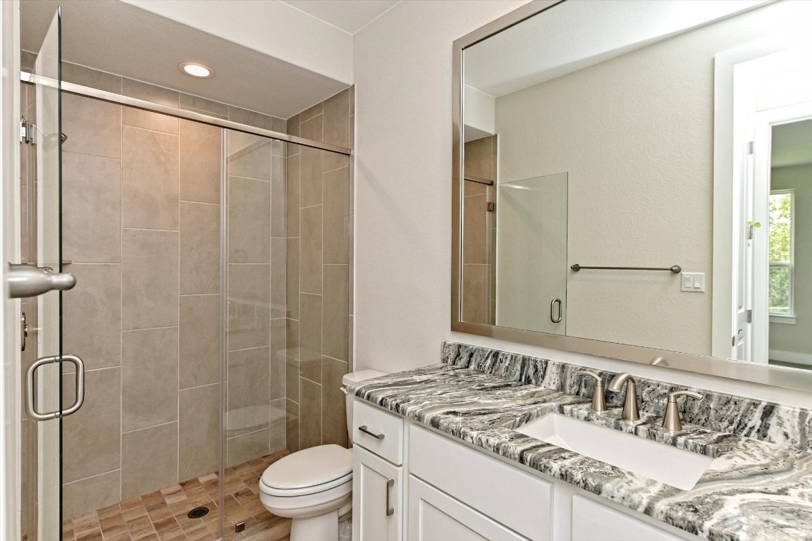 1221 Stormy Drive Georgetown, TX 78628 - Photo 28 of 33 a bathroom with a granite countertop sink a toilet and shower