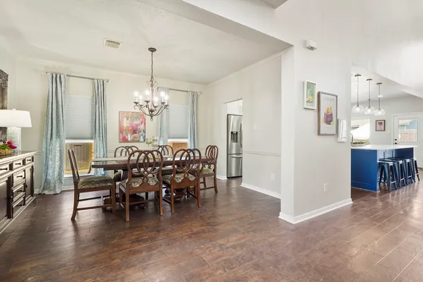 a view of a dining room and livingroom with furniture wooden floor a chandelier