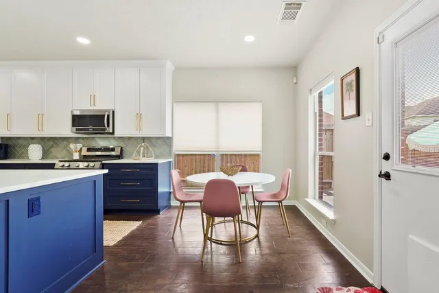 a kitchen with stainless steel appliances granite countertop a stove top oven a sink a dining table and chairs with wooden floor