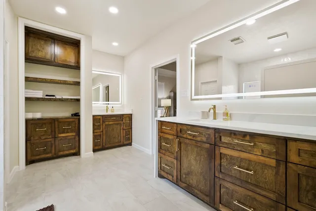 a spacious bathroom with a double vanity sink a large mirror and a bathtub