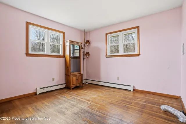a view of an empty room with window and wooden floor