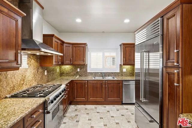 a kitchen with stainless steel appliances granite countertop a stove a sink and a refrigerator