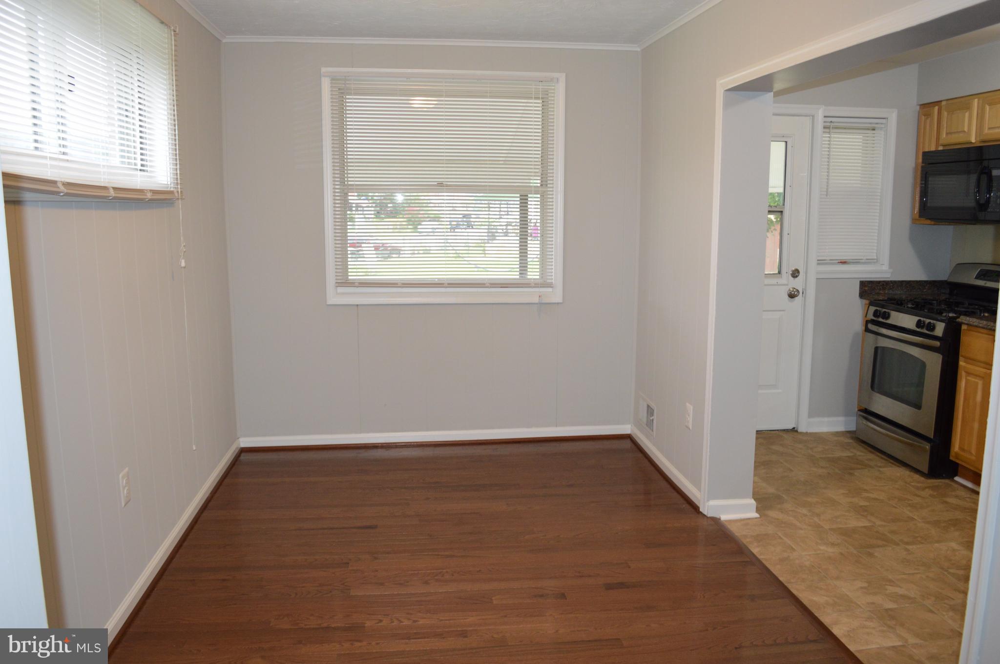 8223 Kavanagh Road Baltimore, MD 21222 - Photo 7 of 17 an empty room with windows fireplace and wooden floor