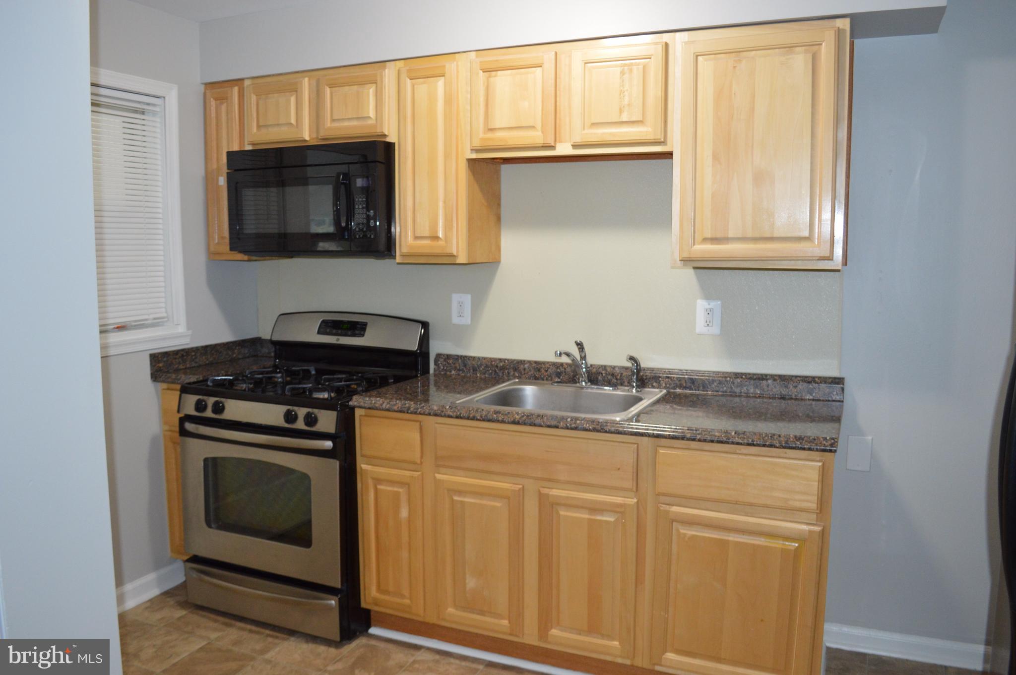 8223 Kavanagh Road Baltimore, MD 21222 - Photo 8 of 17 a kitchen with granite countertop a sink and a stove top oven