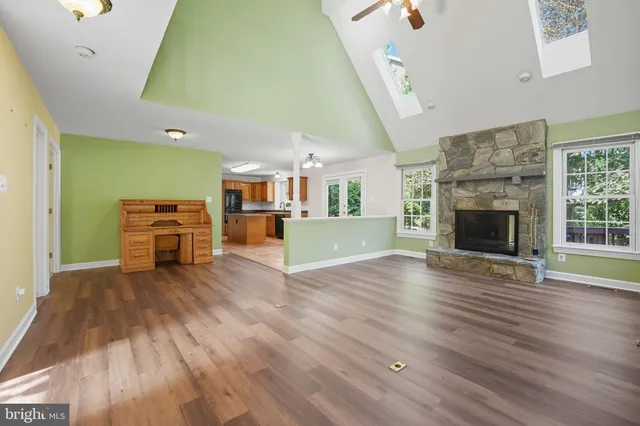 an empty room with wooden floor fireplace and windows