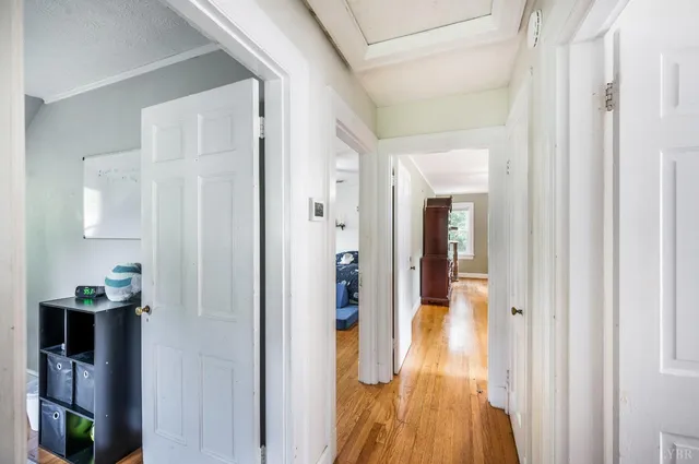 a view of a hallway with wooden floor and a bathroom