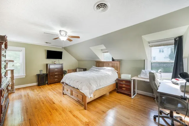 a spacious bedroom with a bed and a flat tv screen on wall