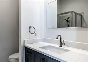 a bathroom with a granite countertop sink a toilet and mirror