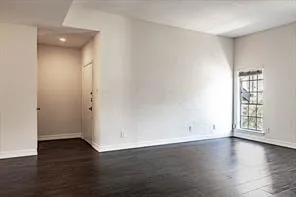 an empty room with wooden floor and window