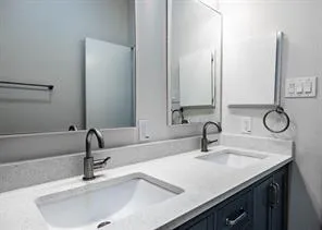 a bathroom with double vanity sinks and a mirror