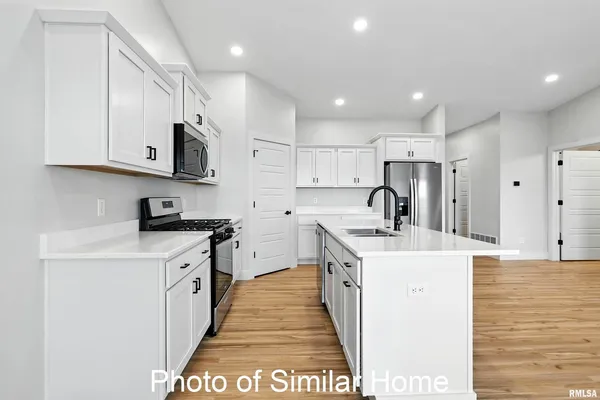 a kitchen with stainless steel appliances a sink a stove a refrigerator a white counter top and white cabinets