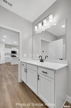 a view with double vanity sink a mirror a lamp and a refrigerator