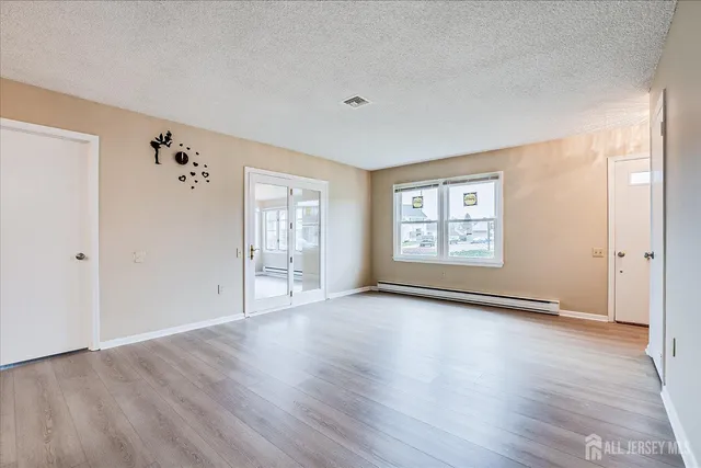 an empty room with wooden floor and windows