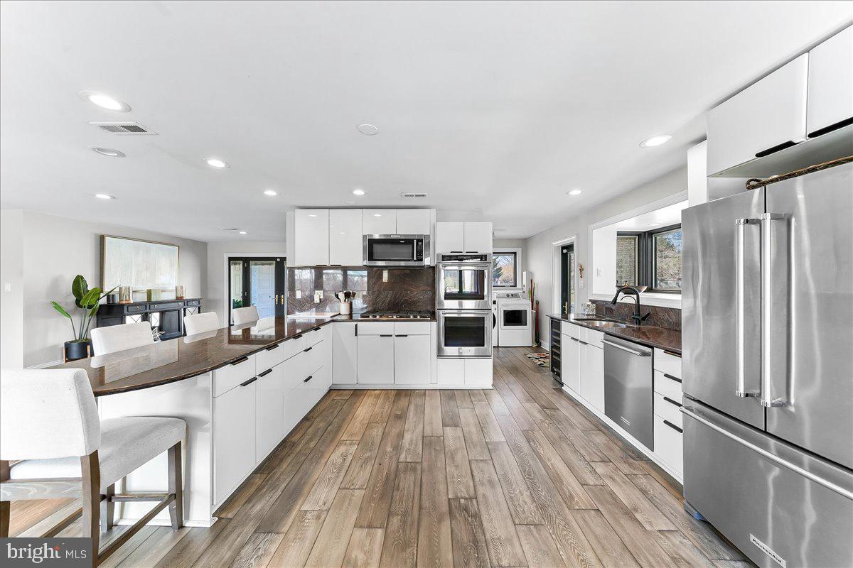 1056 Lenape Road West Chester, PA 19382 - Photo 14 of 48 a large white kitchen with wooden floor and stainless steel appliances