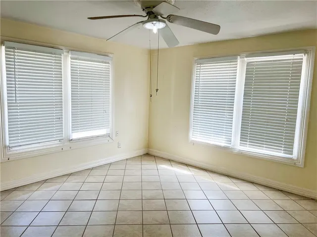 a view of an empty room with a window and a ceiling fan