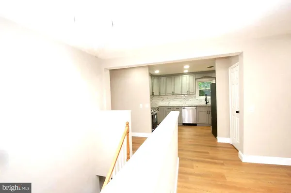 a view of a kitchen with kitchen island a sink wooden floor and a living room view