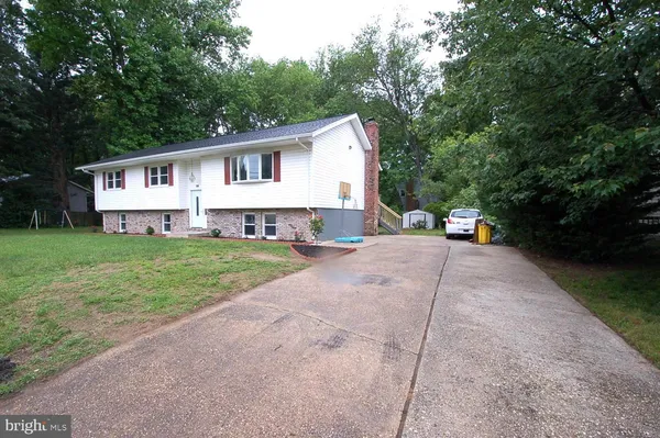 a front view of a house with a yard and large trees