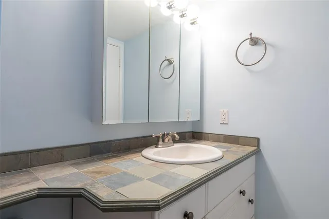 a bathroom with a granite countertop sink and a mirror