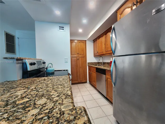 a kitchen with granite countertop a refrigerator and a stove top oven