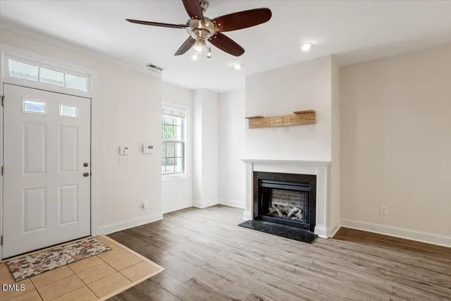 a view of an empty room with wooden floor a fireplace and a window