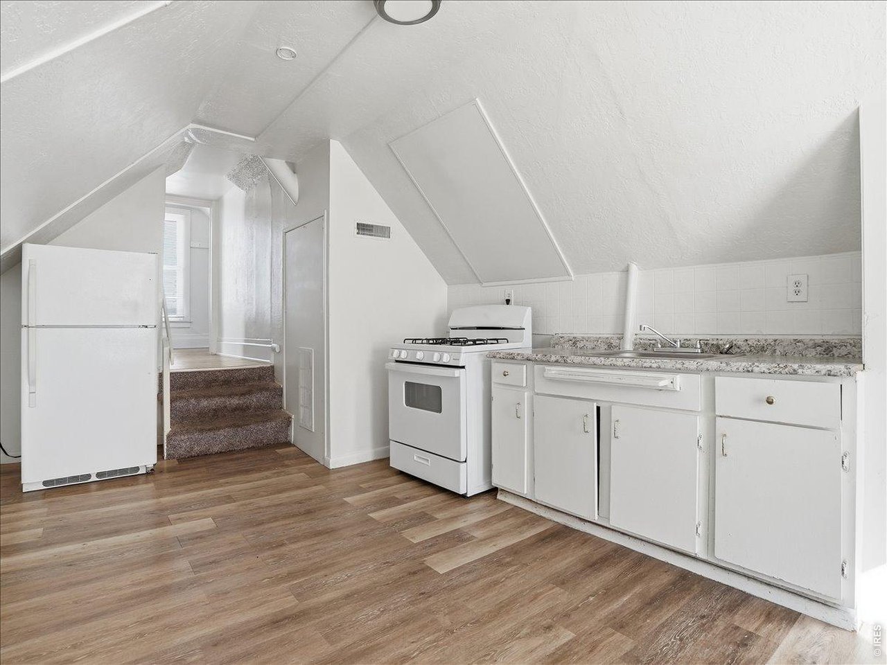 228 13th Street Greeley, CO 80631 - Photo 13 of 29 a kitchen with granite countertop white cabinets and white appliances