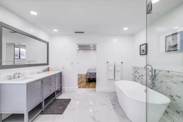 a bathroom with a tub a sink and a mirror