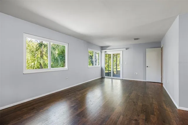 a view of an empty room with wooden floor and a window