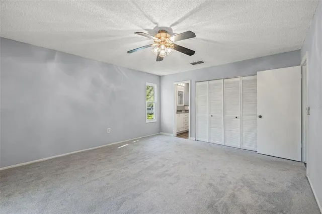 a view of an empty room with chandelier fan and window