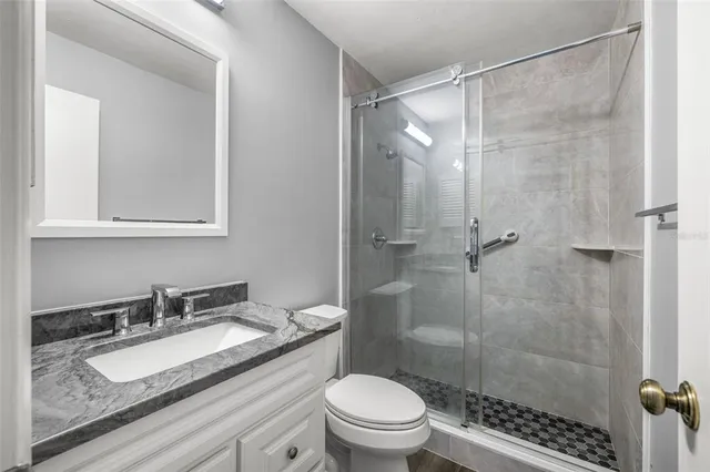 a bathroom with a granite countertop sink a mirror a toilet and shower