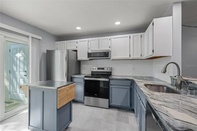 a kitchen with stainless steel appliances granite countertop a stove a sink and a refrigerator