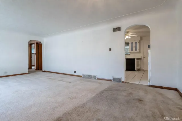 a view of a livingroom with wooden floor and kitchen view