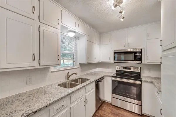 a kitchen with stainless steel appliances granite countertop a sink a stove and cabinets