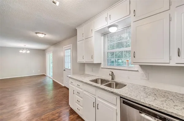 a kitchen with granite countertop a sink window and cabinets