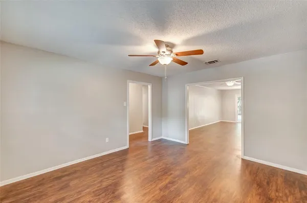 a view of an empty room with window and wooden floor