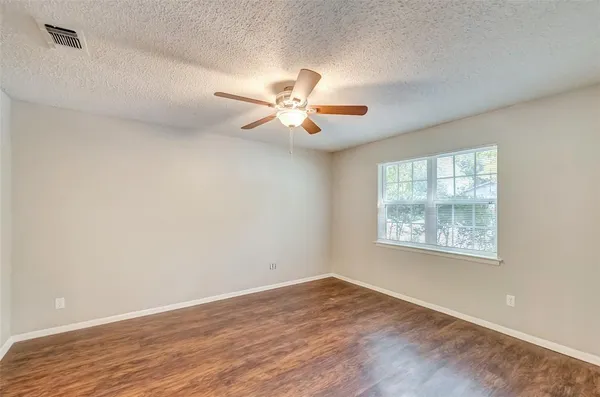 a view of an empty room with a window and wooden floor