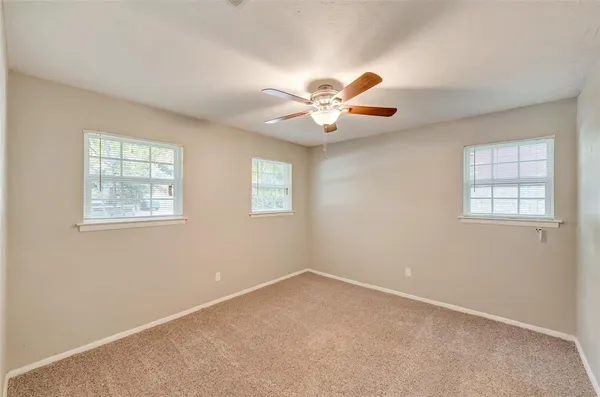 an empty room with windows and chandelier fan