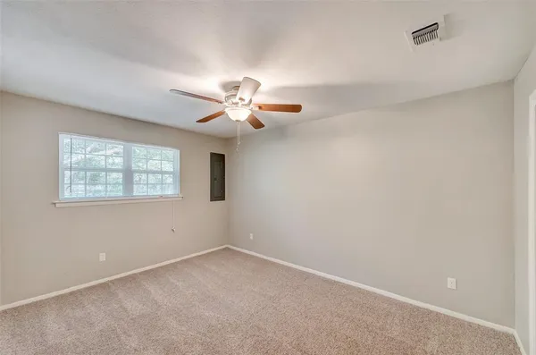 an empty room with a chandelier fan and windows