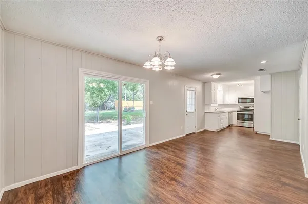 a view of an empty room with window wooden floor and kitchen