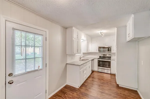 a kitchen with stainless steel appliances a sink and wooden floor