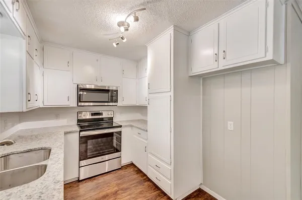 a kitchen with stainless steel appliances white cabinets and a stove a refrigerator with wooden floor