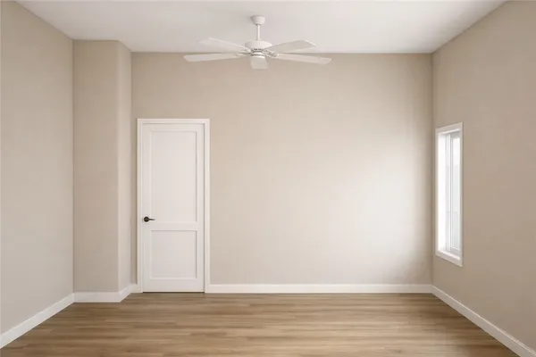 an empty room with wooden floor and fan