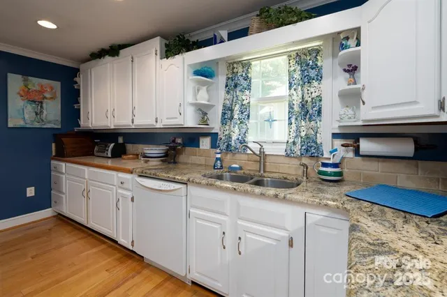 a kitchen with granite countertop a sink window and cabinets