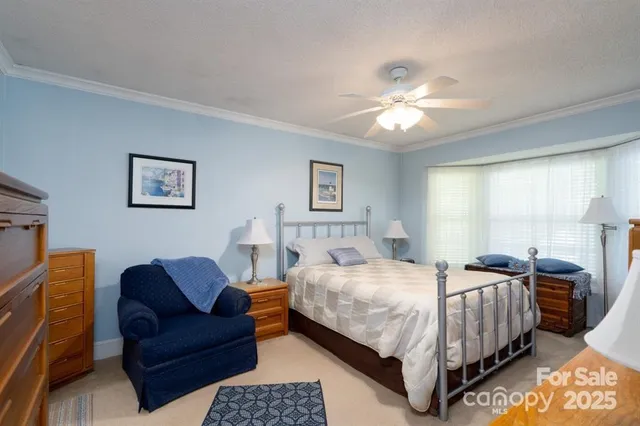 a bedroom with a bed couch chandelier and a window