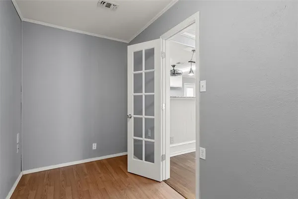 a view of an empty room with wooden floor and kitchen