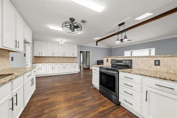 a large kitchen with cabinets wooden floor and stainless steel appliances