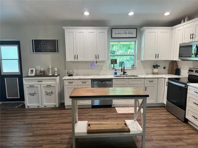 a kitchen with stainless steel appliances kitchen island wooden cabinets a dining table and chairs