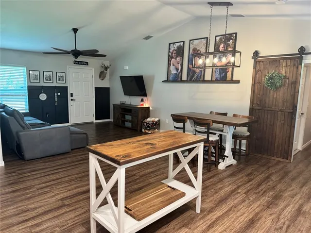 a kitchen with stainless steel appliances kitchen island granite countertop a table chairs and a refrigerator