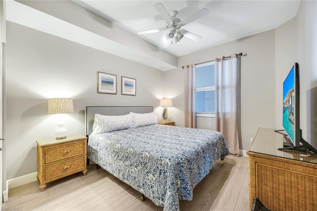 470 Launch Circle, Unit 403 Naples, FL 34108 - Photo 11 of 25 a bedroom with a bed and a flat tv screen on dresser