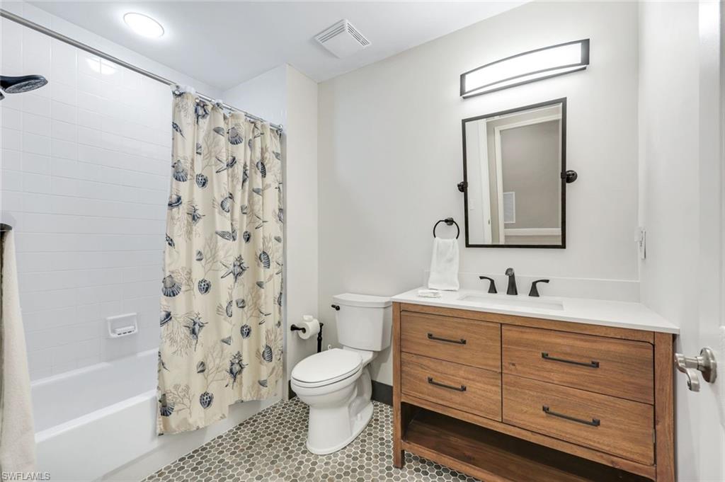 470 Launch Circle, Unit 403 Naples, FL 34108 - Photo 12 of 25 a bathroom with a toilet sink a mirror a shower and vanity